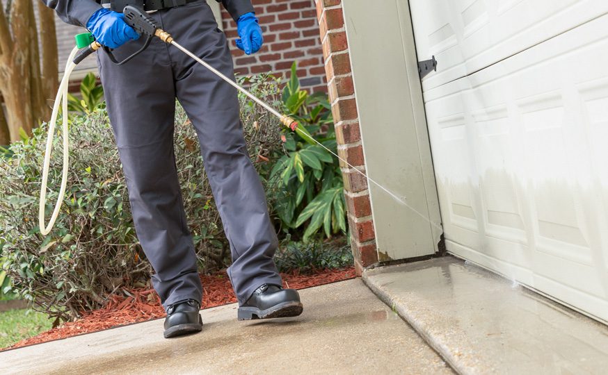 Exterminator spraying termite barrier outside house