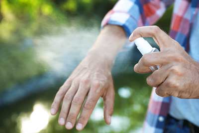 Hands spraying bug spray on arm 