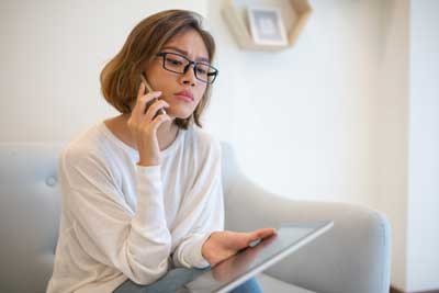 Serious woman on phone with laptop