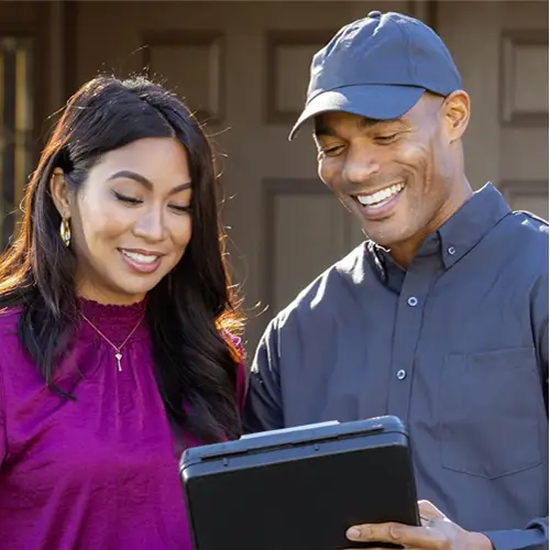 Tech speaking with a customer in front of a house | Suburban Exterminating Pest Control serving NY