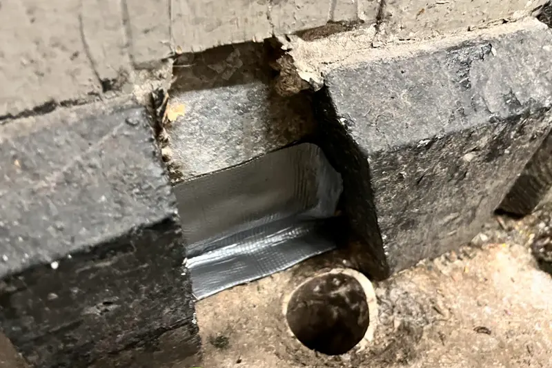 Flexi Armour tape being used by Suburban Exterminating to seal the gap space between an expansion joint.