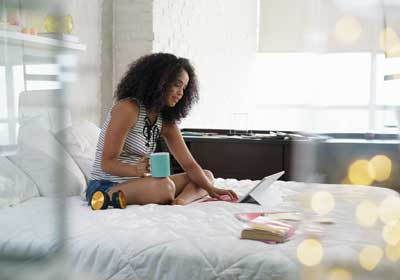 Woman on bed with coffee and tablet